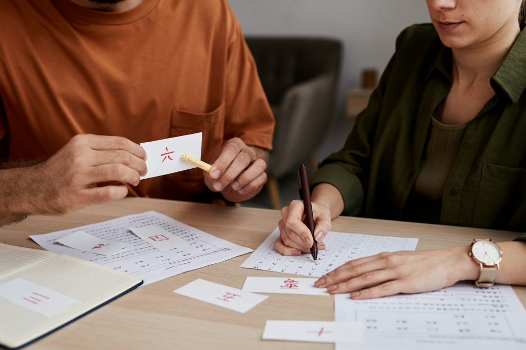 Male tutor of Chinese language pointing at paper card with hieroglyph